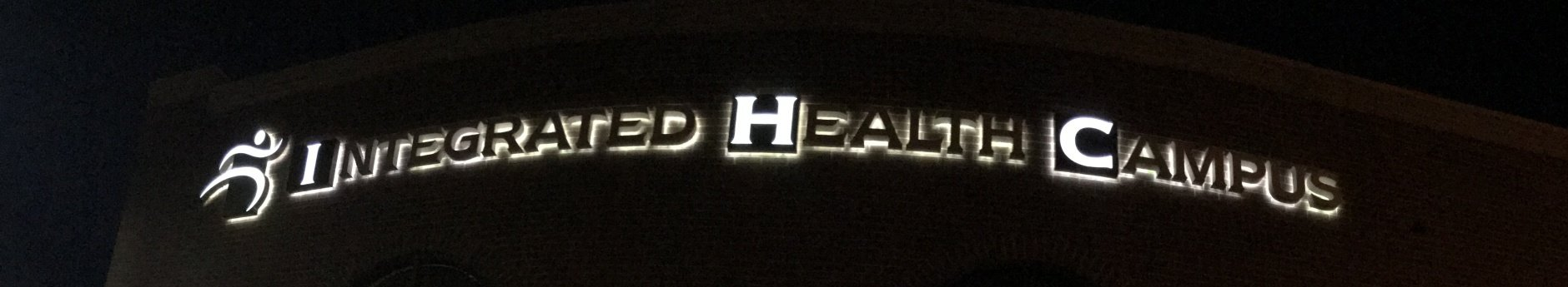 Integrated Health Campus sign lit up at night time.