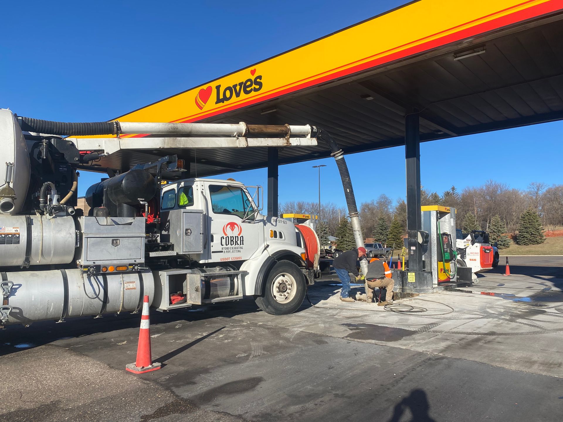 Tow truck refueling under a Loves gas station canopy on a sunny day