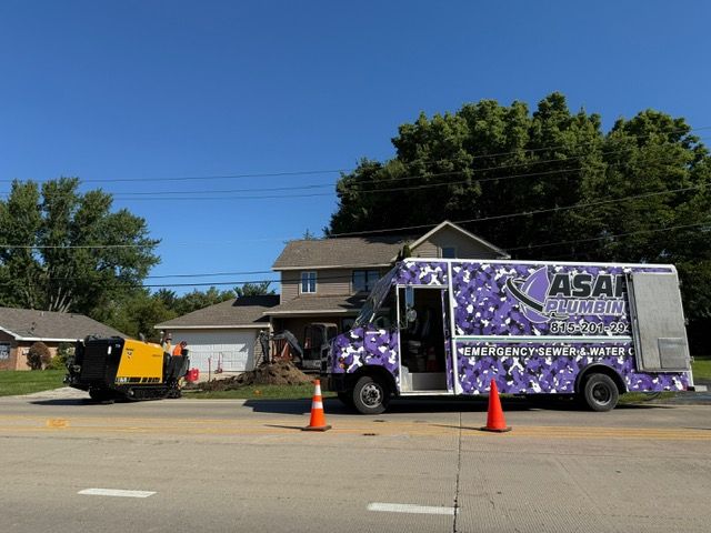 A utility truck with a purple camouflage design parked on a street in front of a house with construction work.