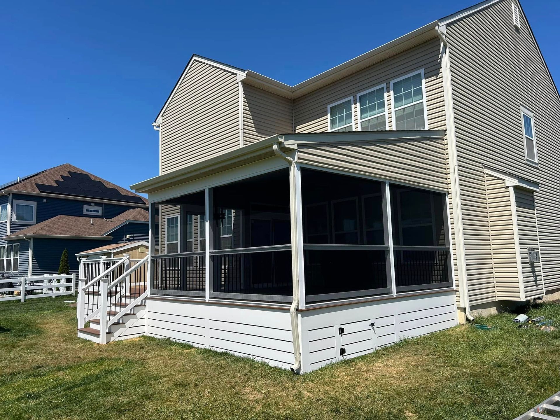 Two-story house with a screened porch and white trim on a sunny day.