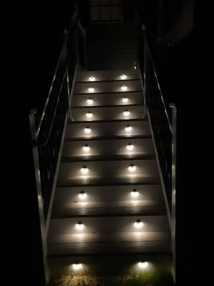 Staircase illuminated by small lights on each step, viewed at night.