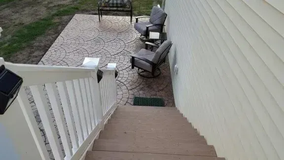 Stairs leading down to a patio with outdoor seating. The patio is stamped concrete and next to the house.