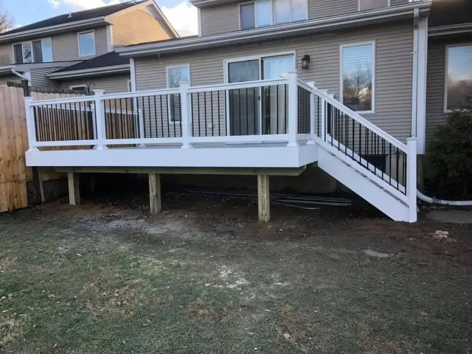 White deck with black railing and stairs leading to a backyard with grass.