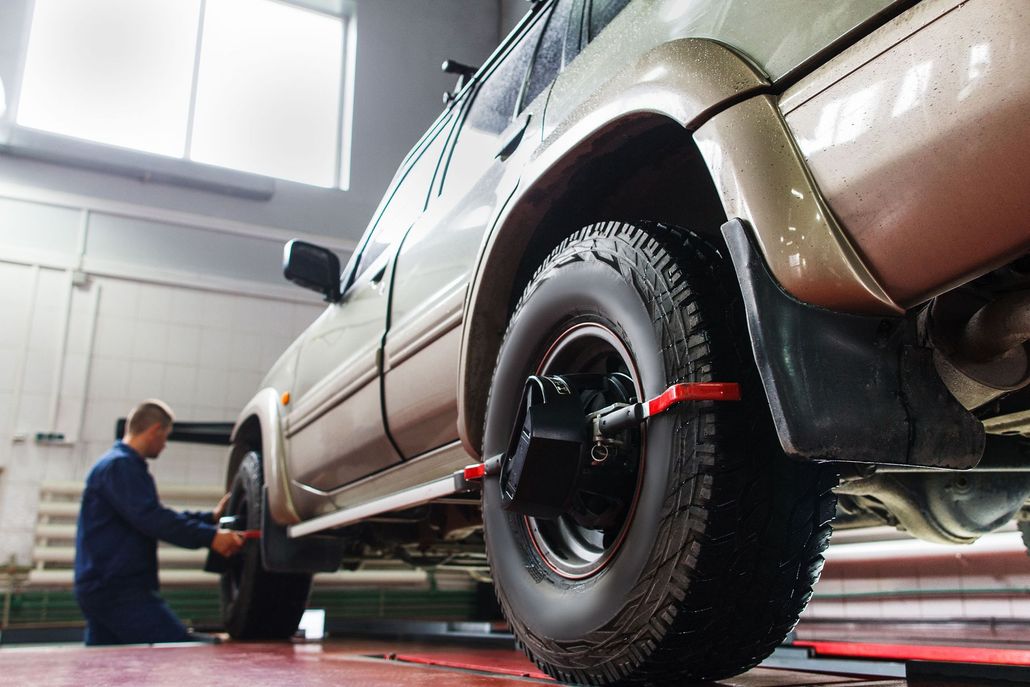 Mechanic aligning a vehicle's tire in a garage, using equipment.