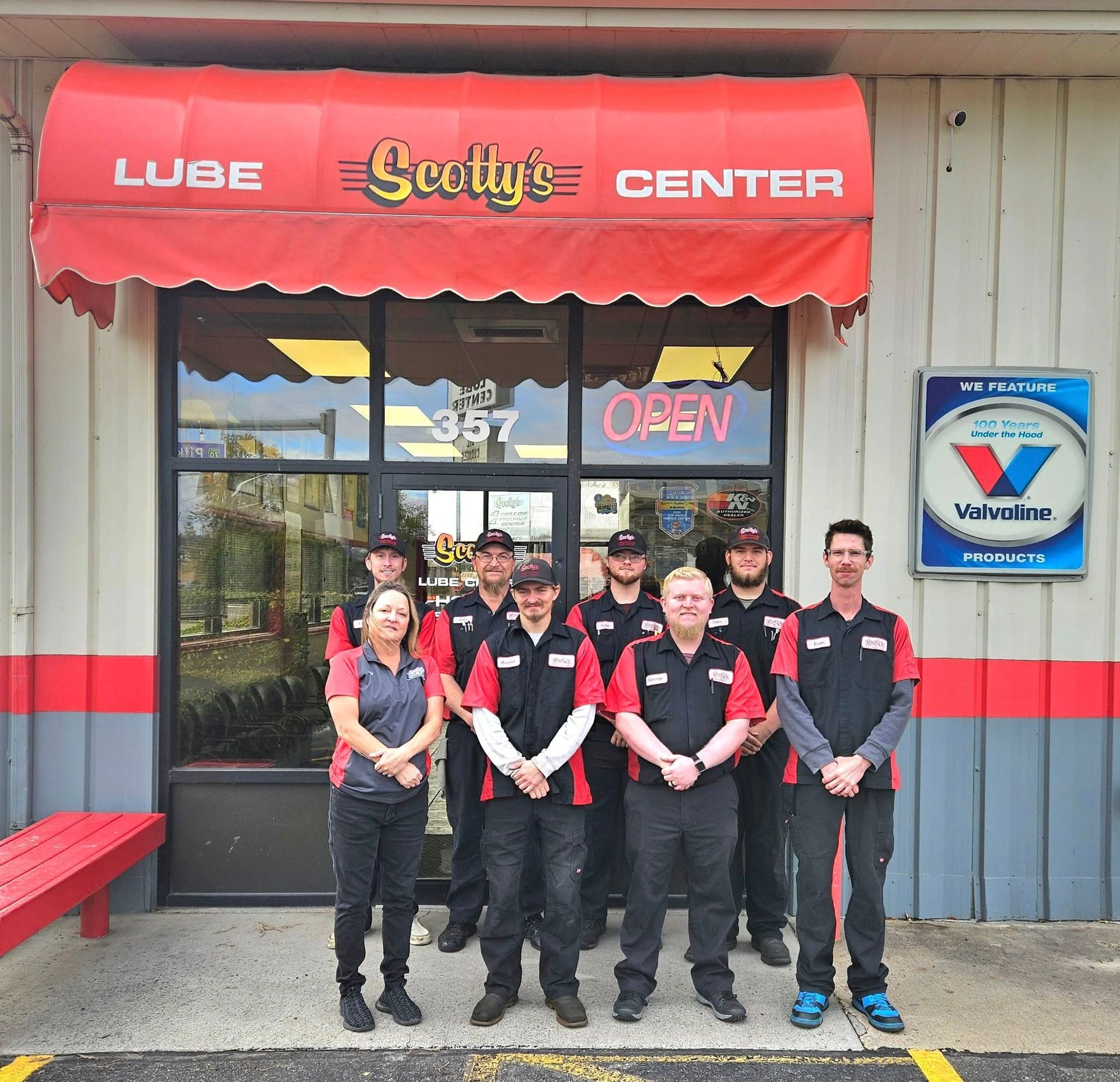Group of employees in uniform stand outside Scotty's Lube Center with red awning.