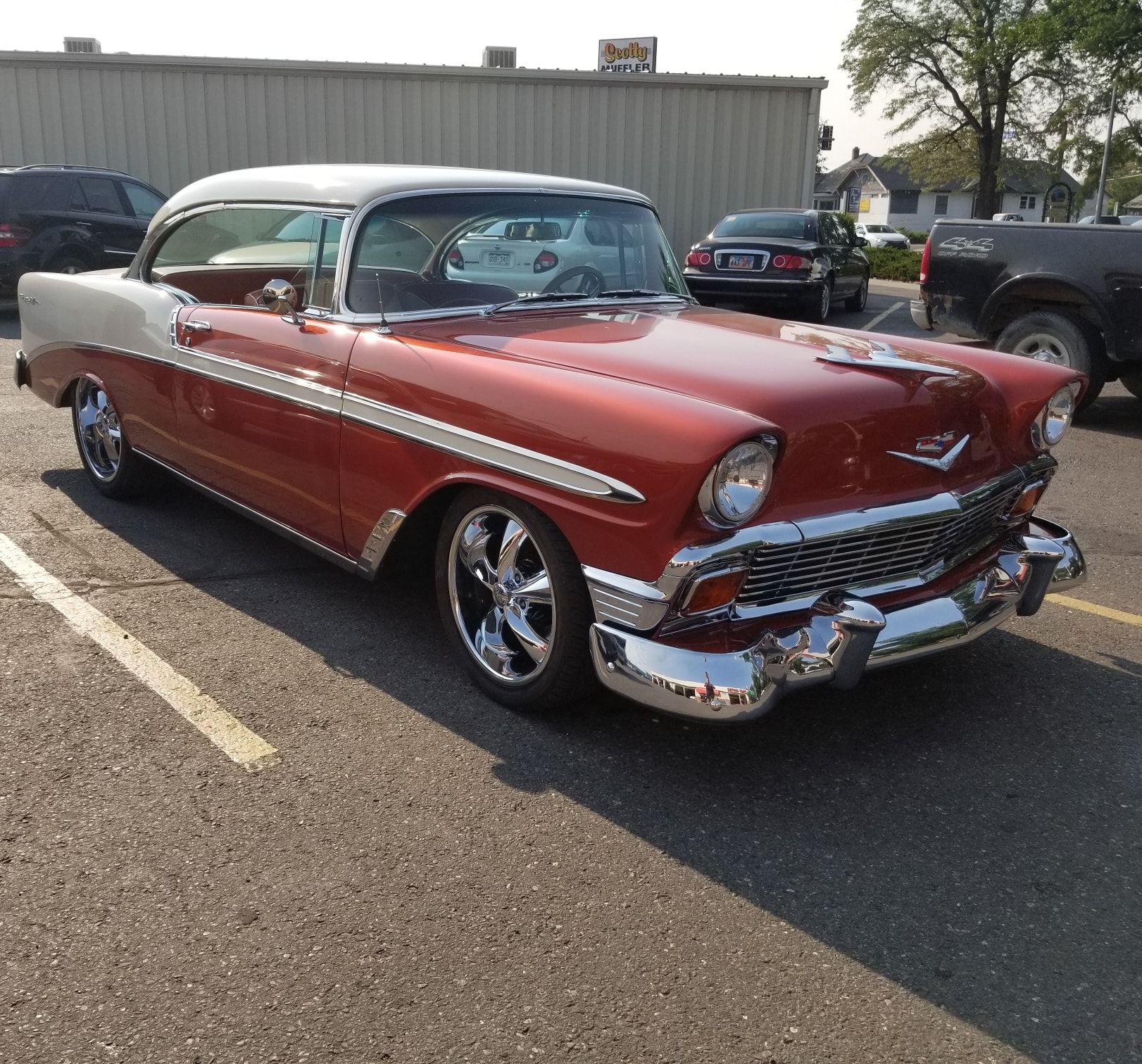 Red and white classic car parked in a lot.