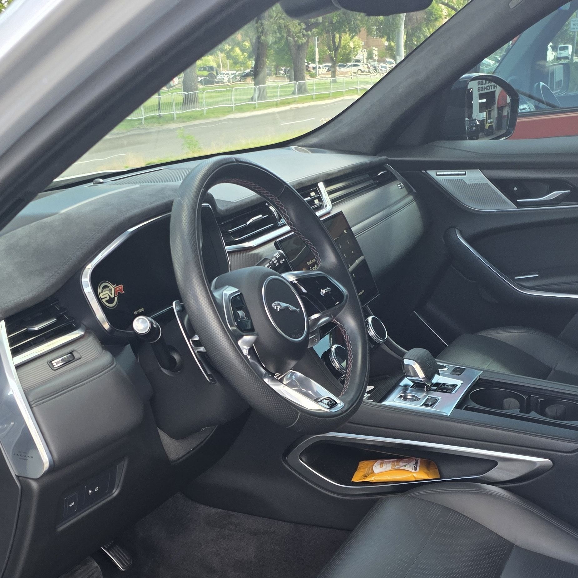 Interior of a black Jaguar car, showing the dashboard, steering wheel, and console.