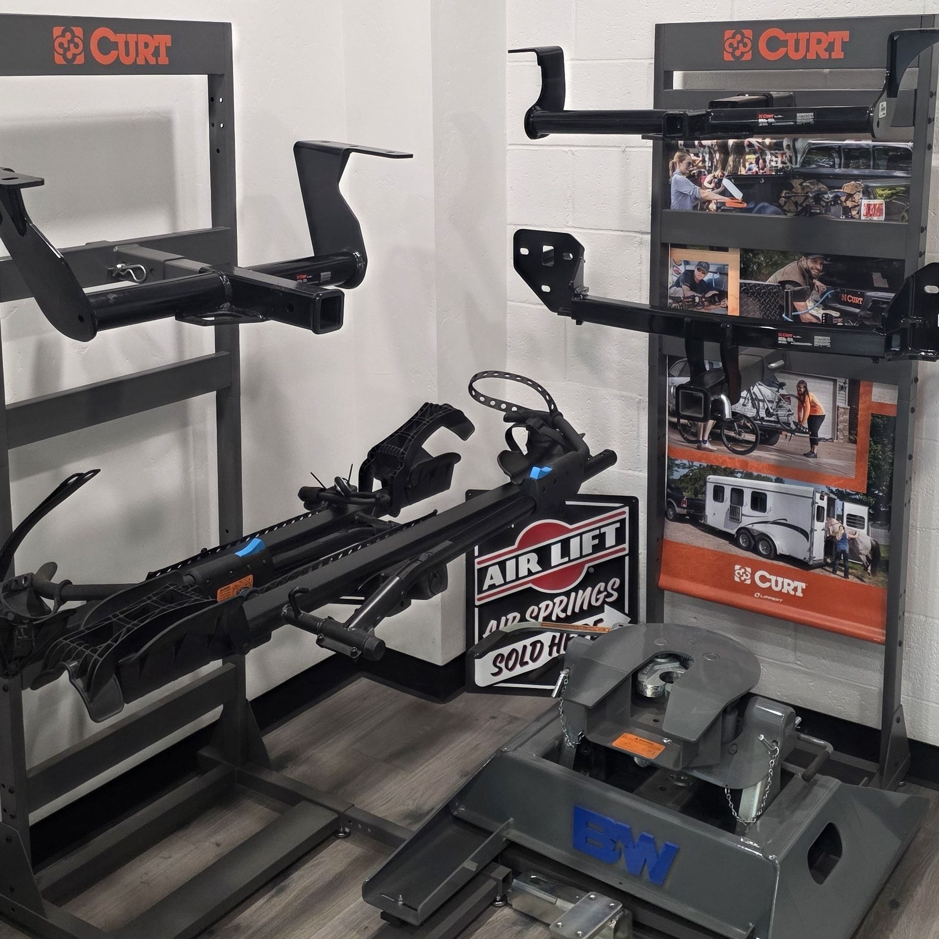 Display of CURT and other brand trailer hitches, near a sign for Air Lift air springs.