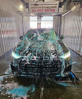 Black car covered in foamy soap at a car wash. 