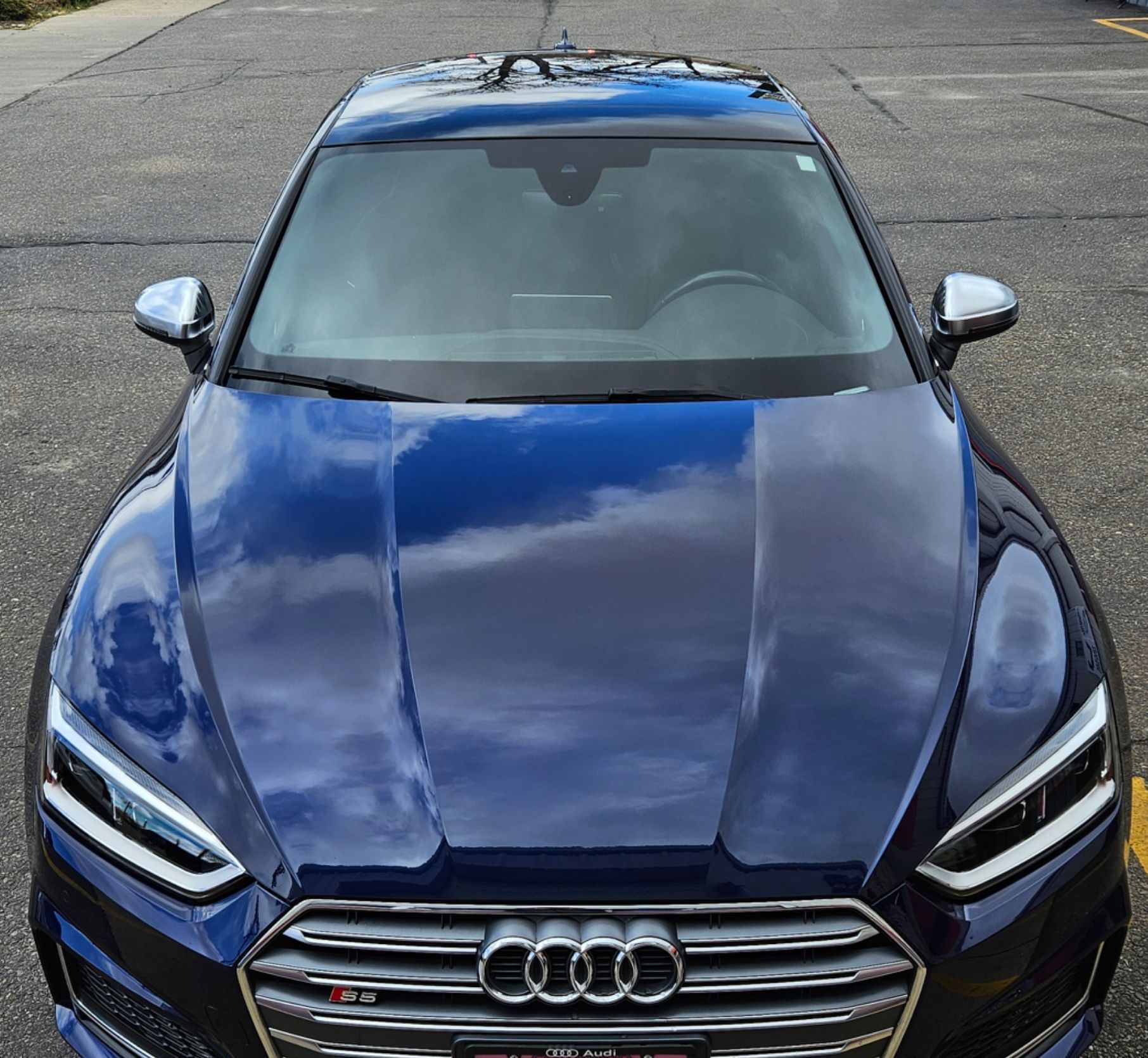 Dark blue Audi S5, front view, parked on asphalt. Reflecting the sky, chrome accents.