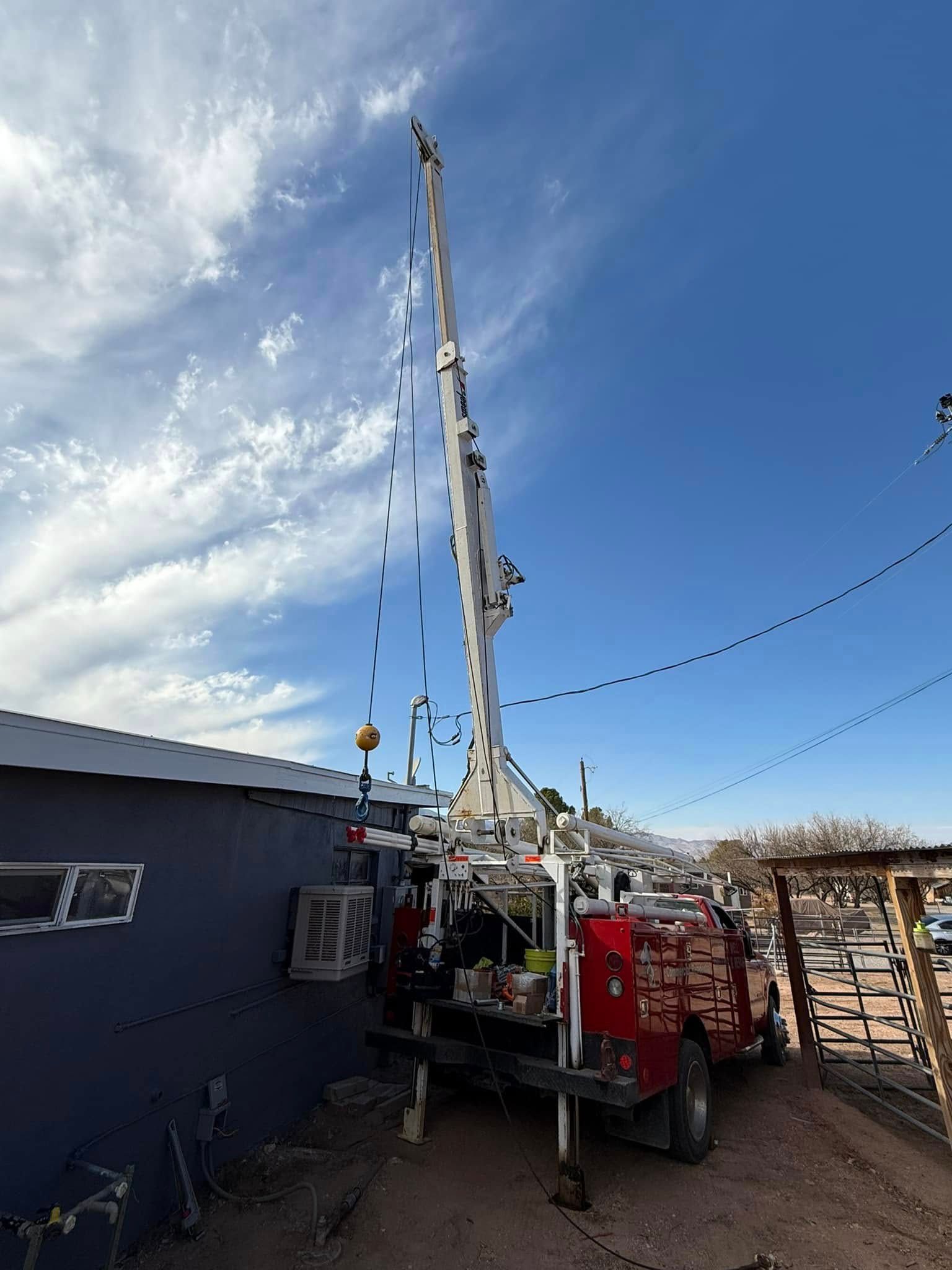 A red truck with a crane on the back is parked in front of a building.