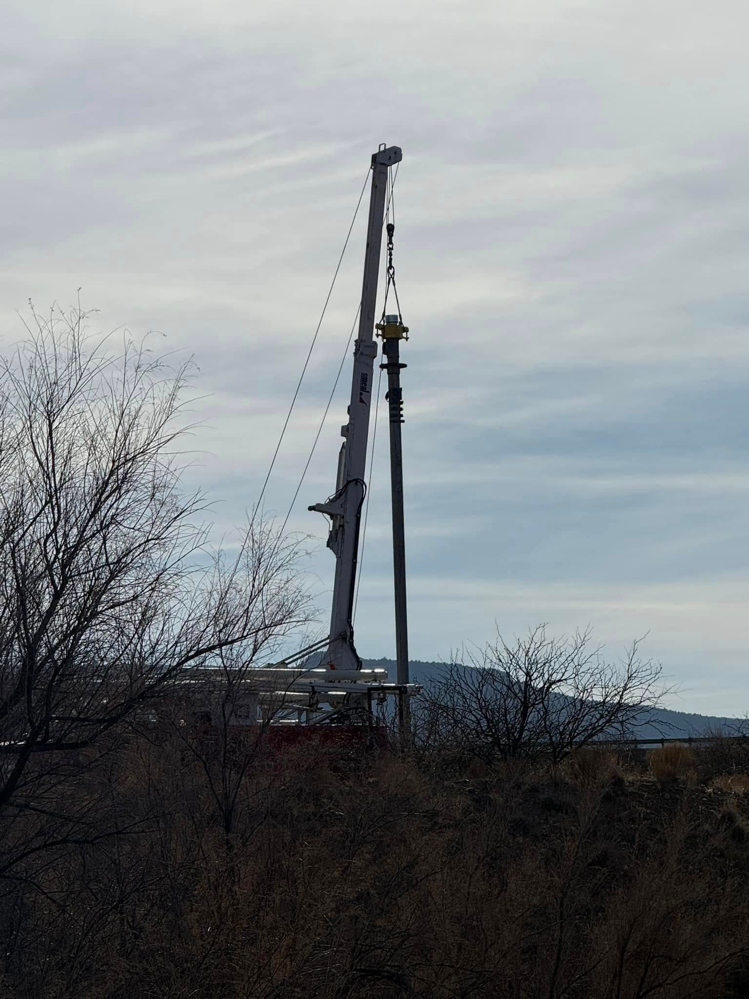 A large crane is silhouetted against a cloudy sky