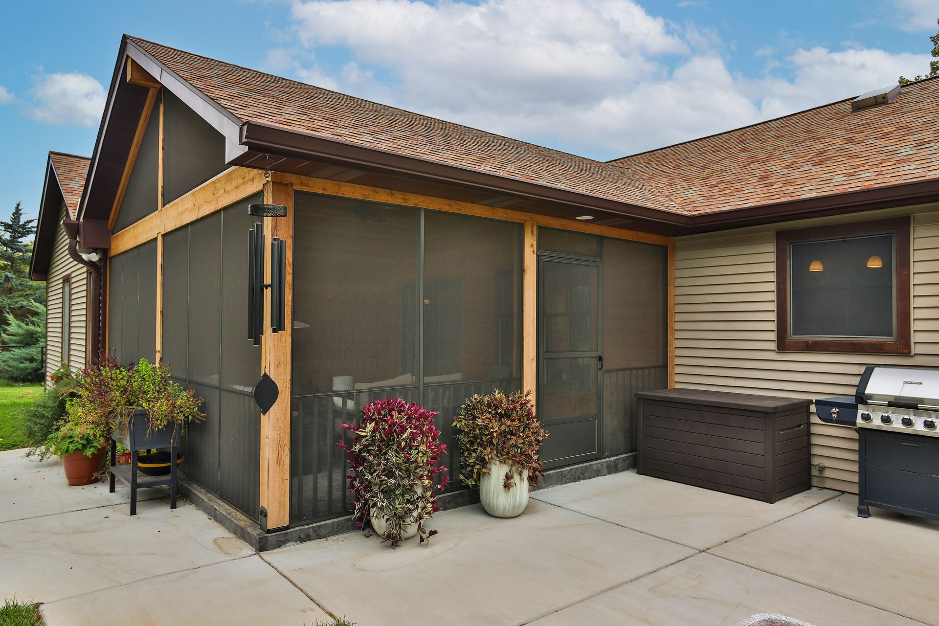 A screened-in porch with a grill and potted plants