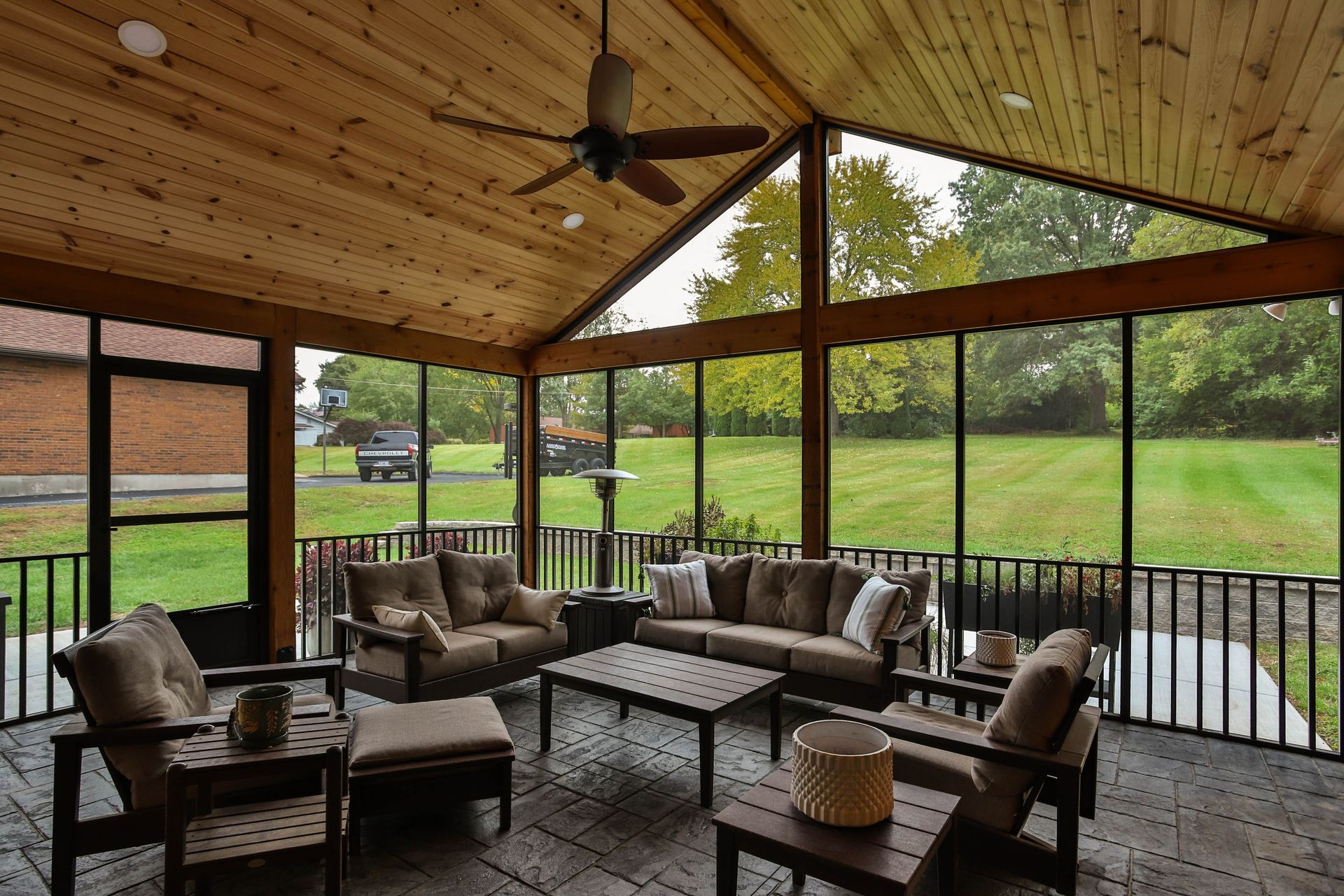 A screened-in porch with furniture and a ceiling fan