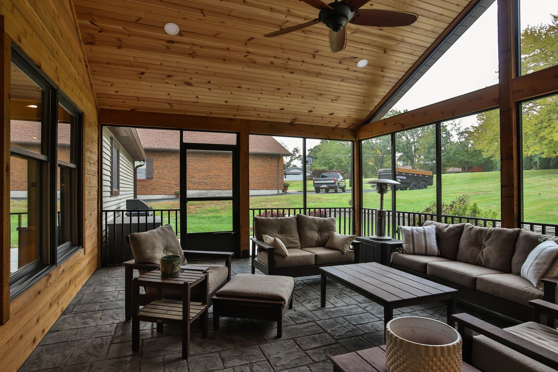 A screened-in porch with a lot of furniture and a ceiling fan