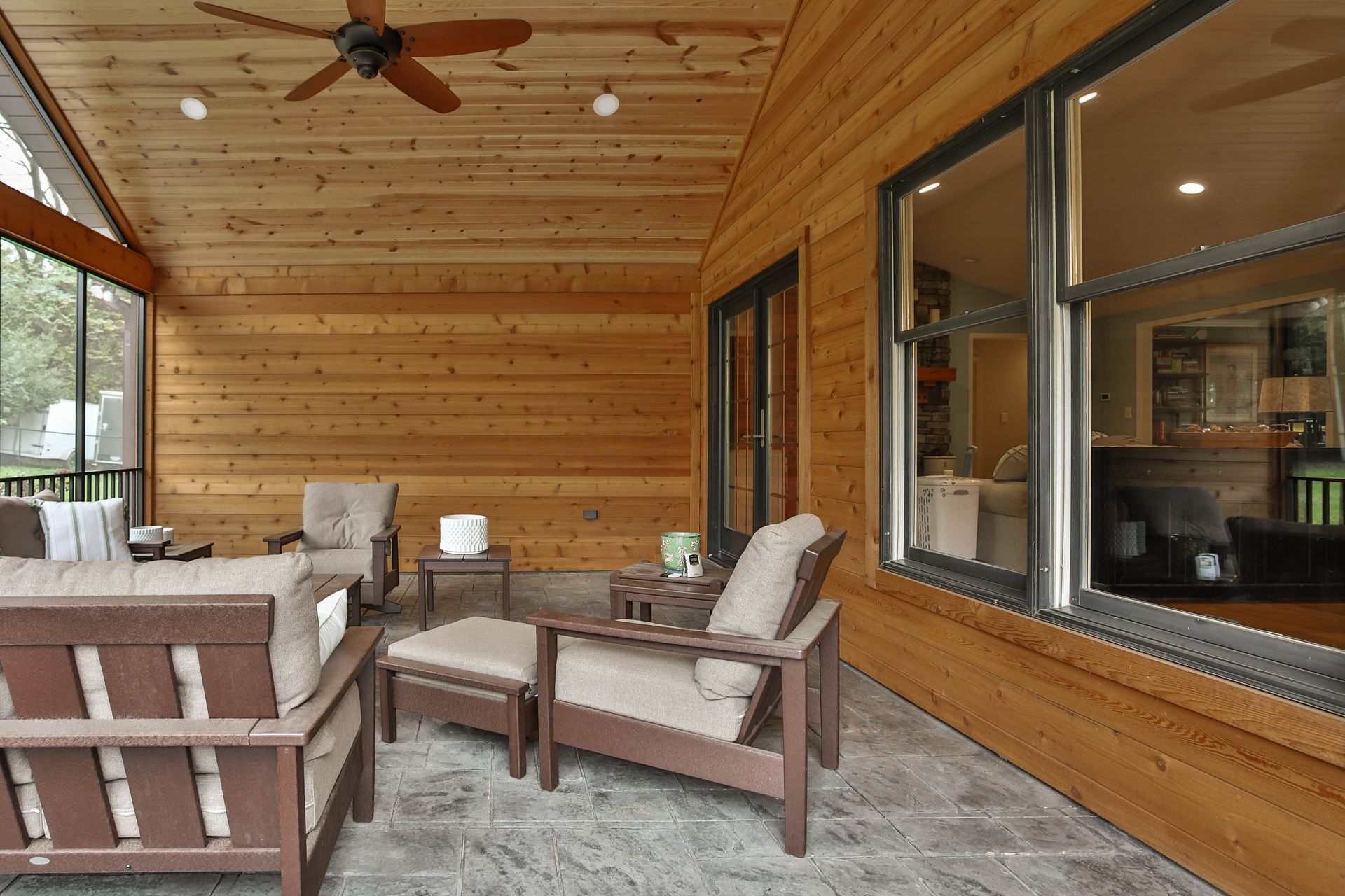 A screened-in porch with furniture and a ceiling fan