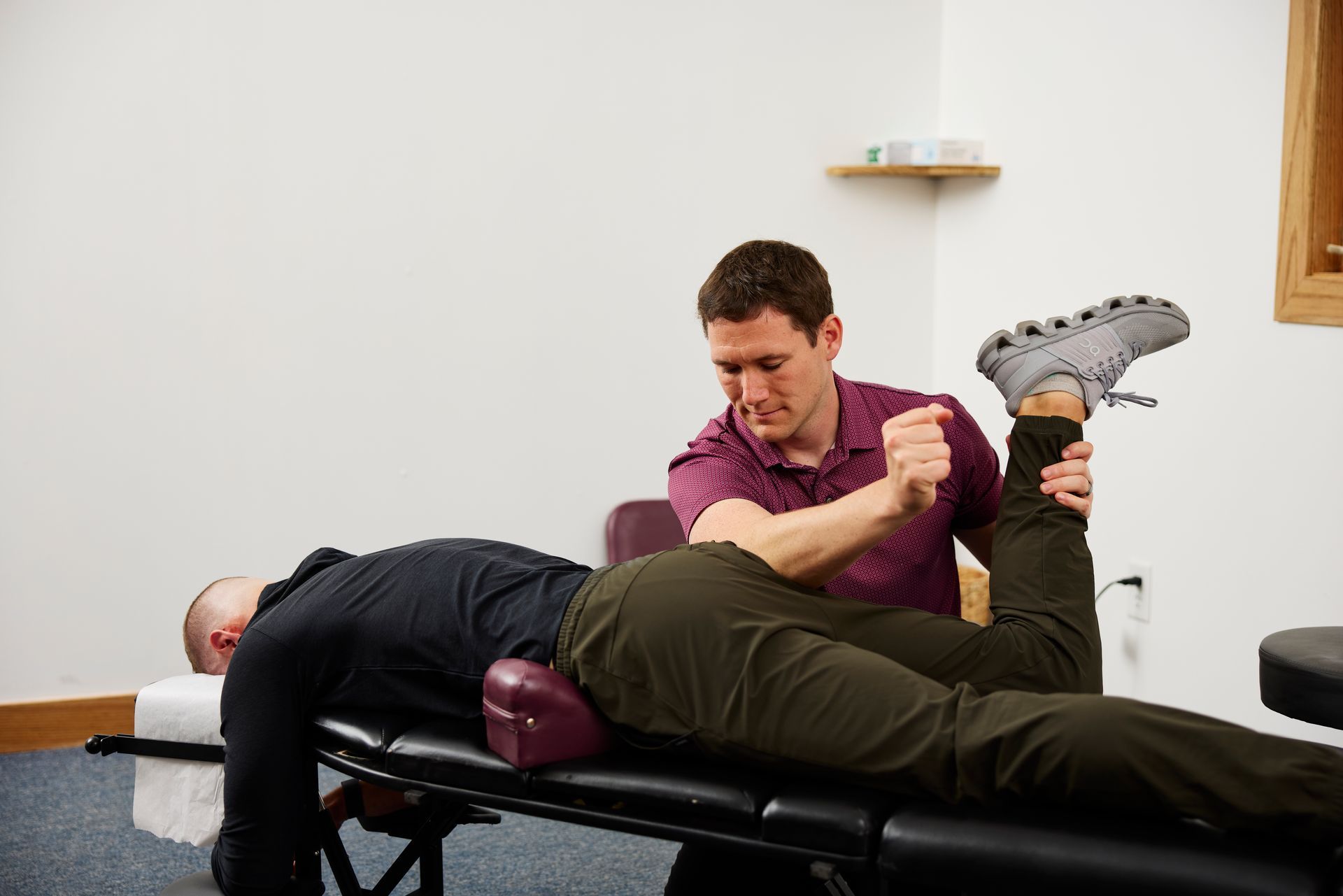 Physical therapist stretching a patient's leg on a treatment table in a clinic room.