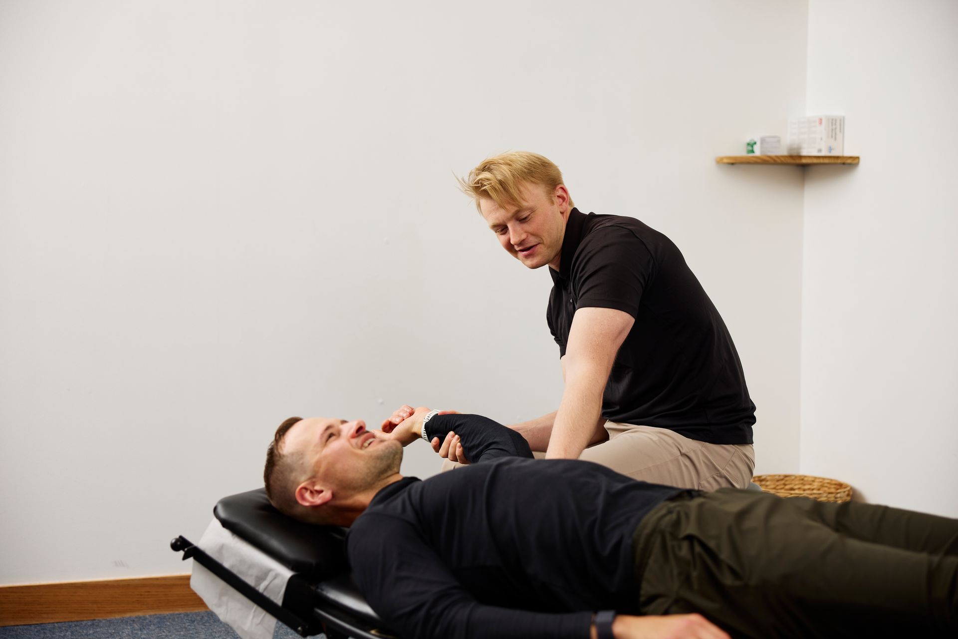 A man receives chiropractic treatment while lying on a table, with a practitioner adjusting his neck.