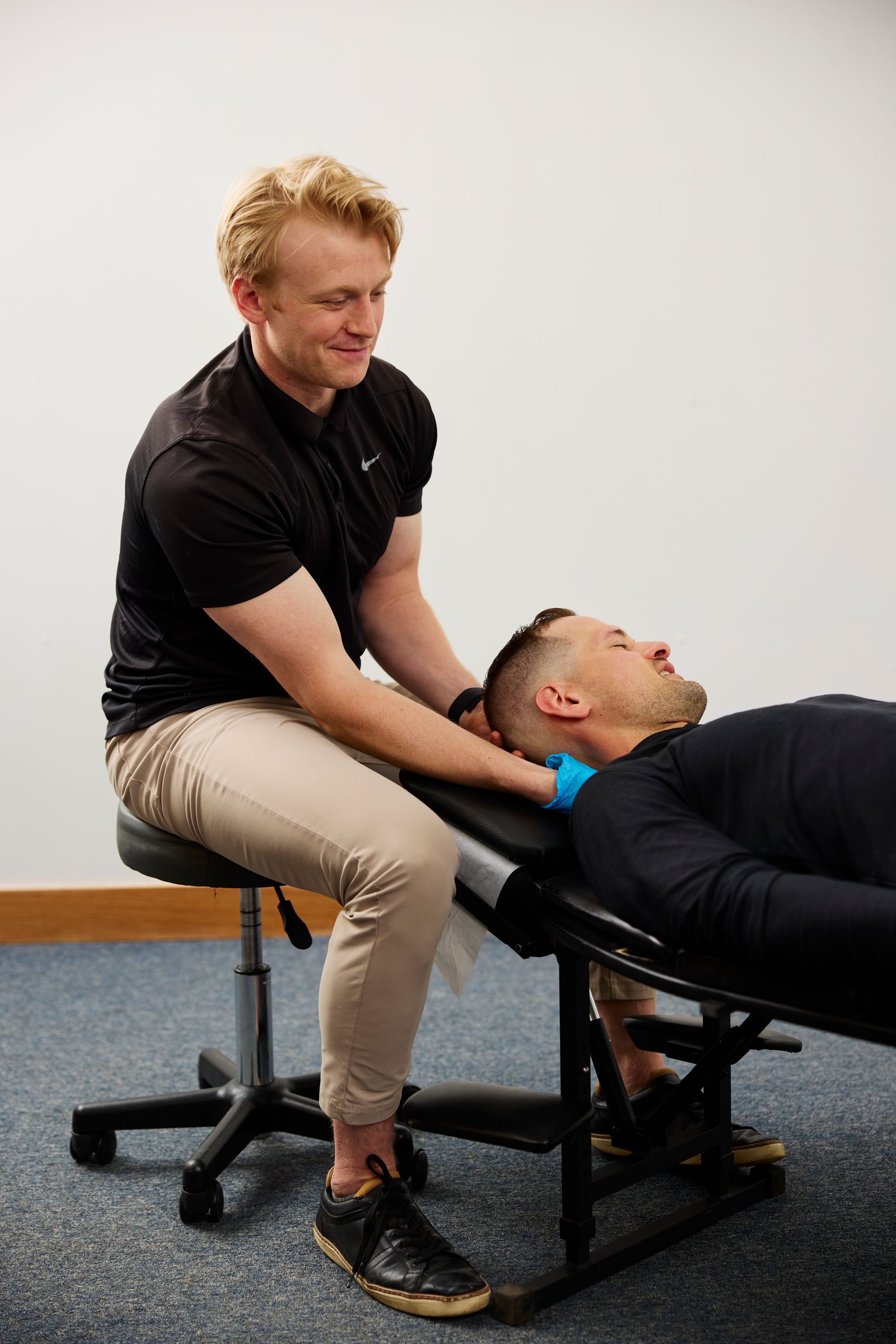 Physical therapist stretching a patient's neck on a treatment table in a clinic room.