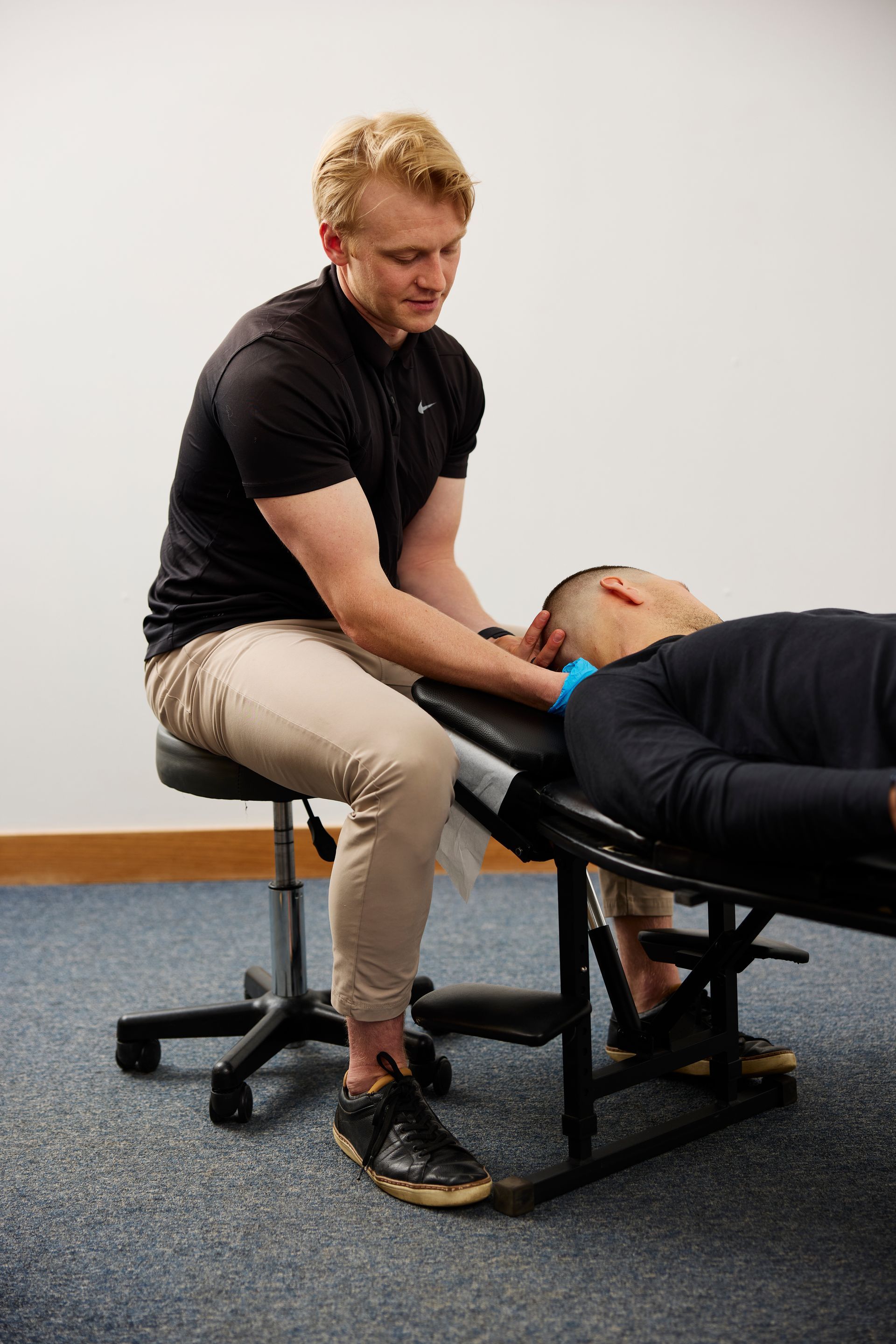 Therapist stretching a client’s leg on a treatment table in a clinic room.