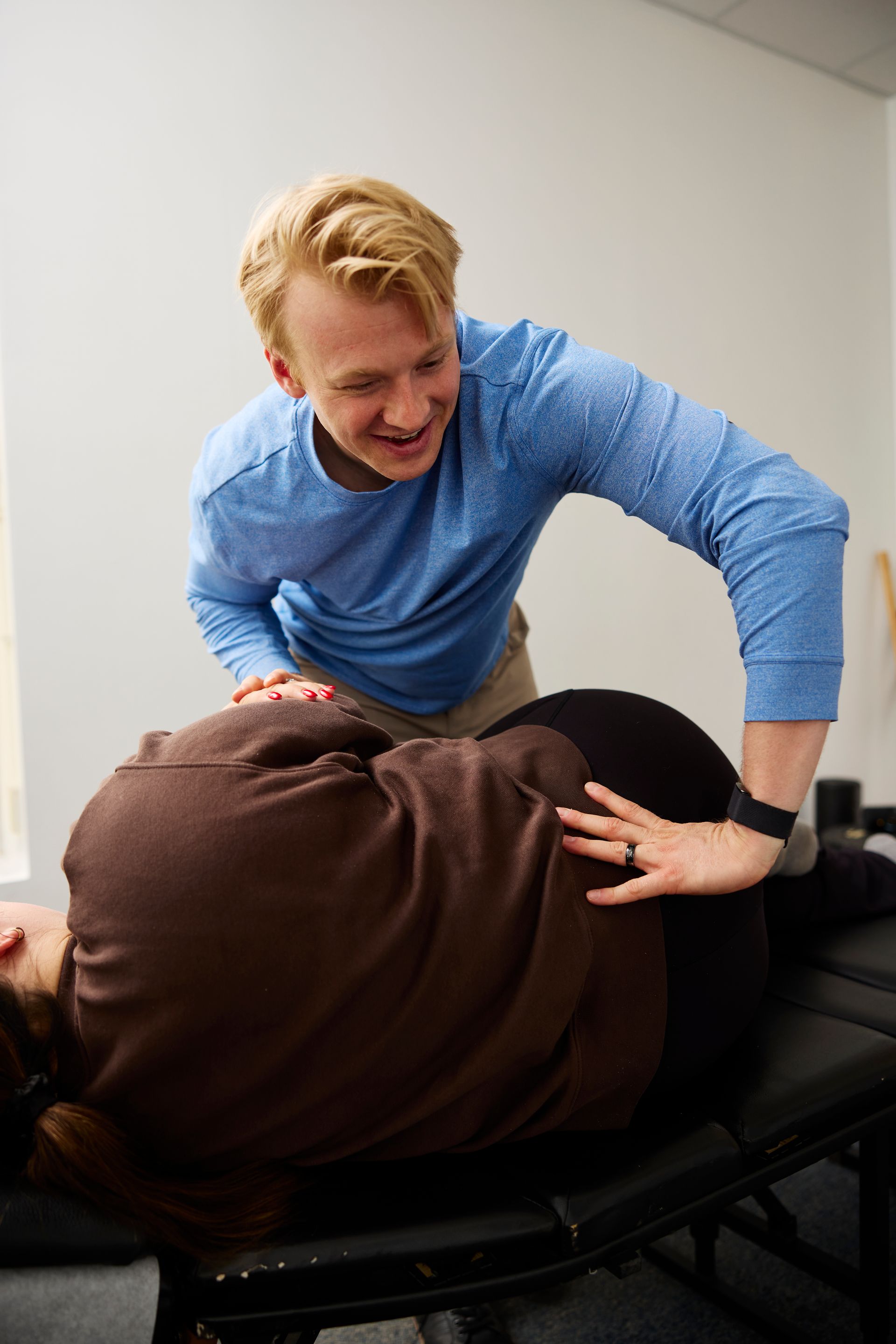 Physical therapist assisting a patient on a treatment table in a clinic room.