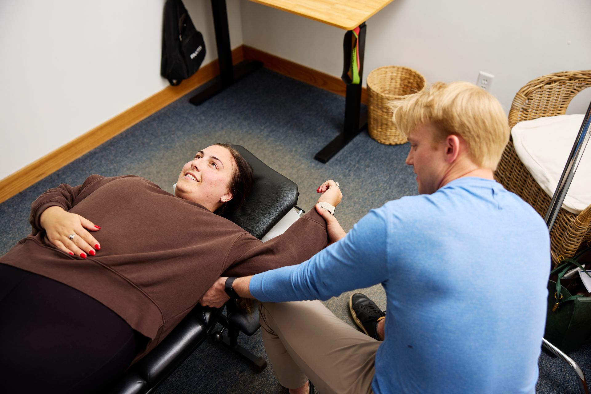 Physical therapy session with a patient on a mat while a therapist assists her leg.