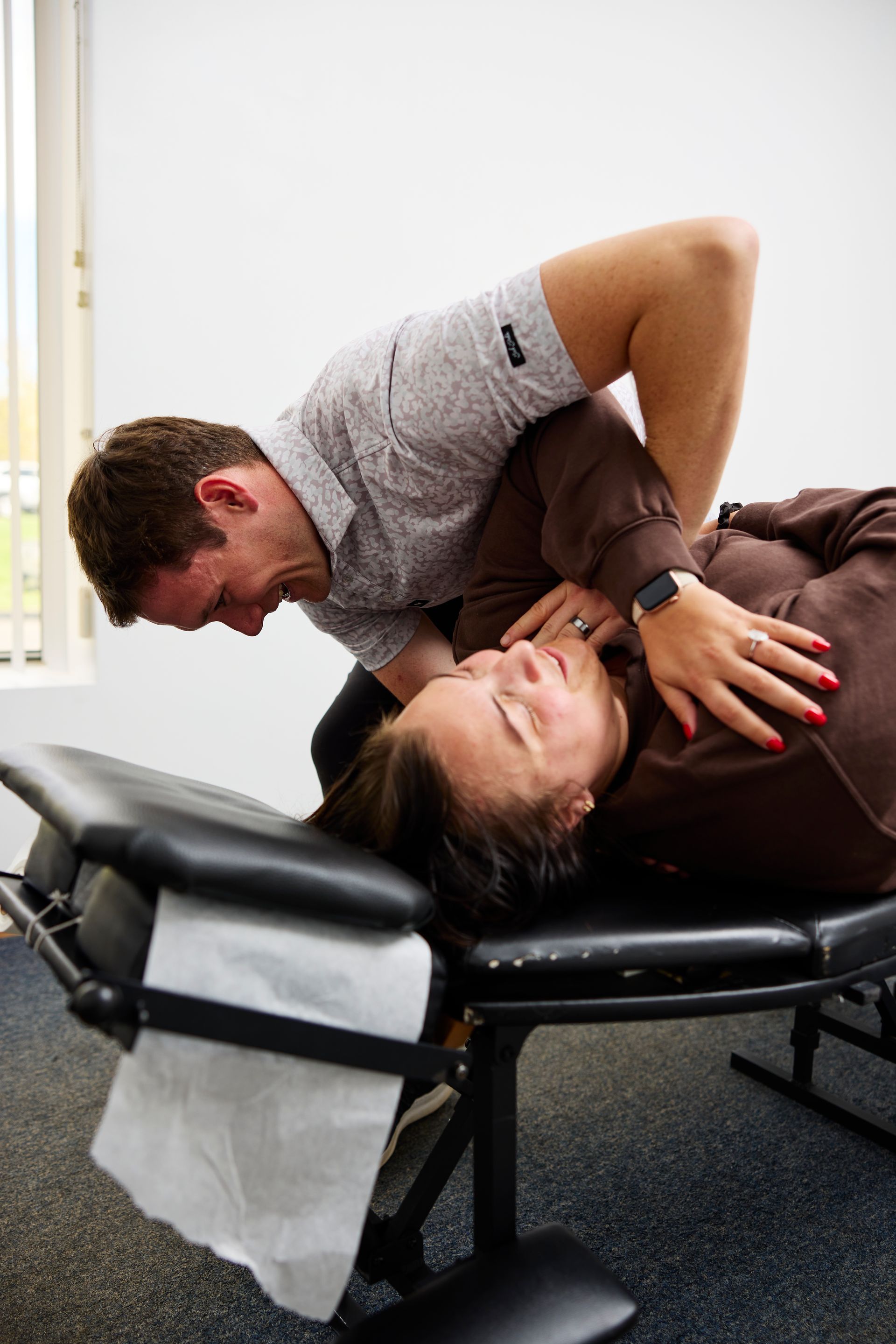 Chiropractor adjusting a patient lying on a treatment table in a clinic.