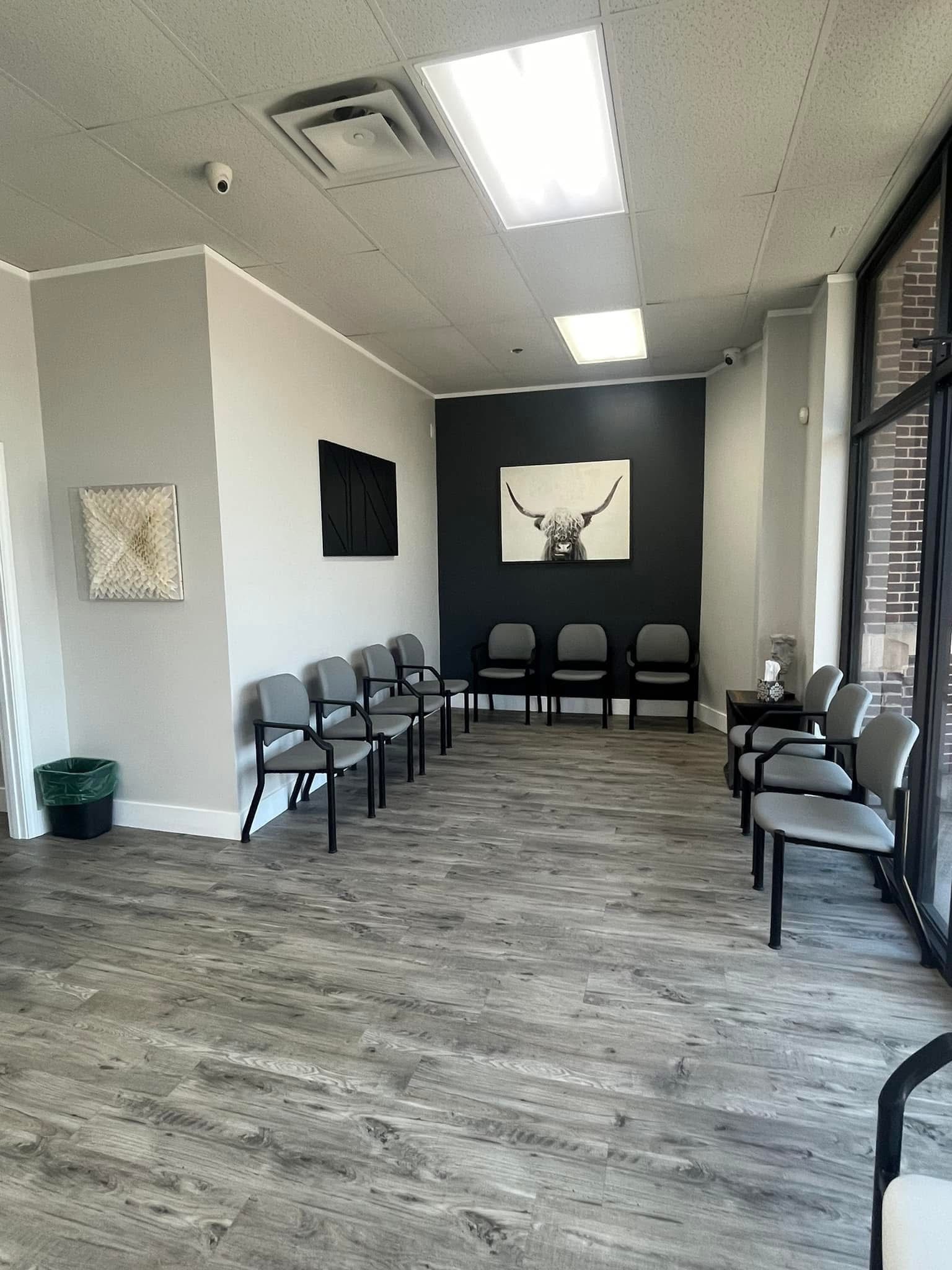 A waiting room with chairs and a picture of a deer on the wall.