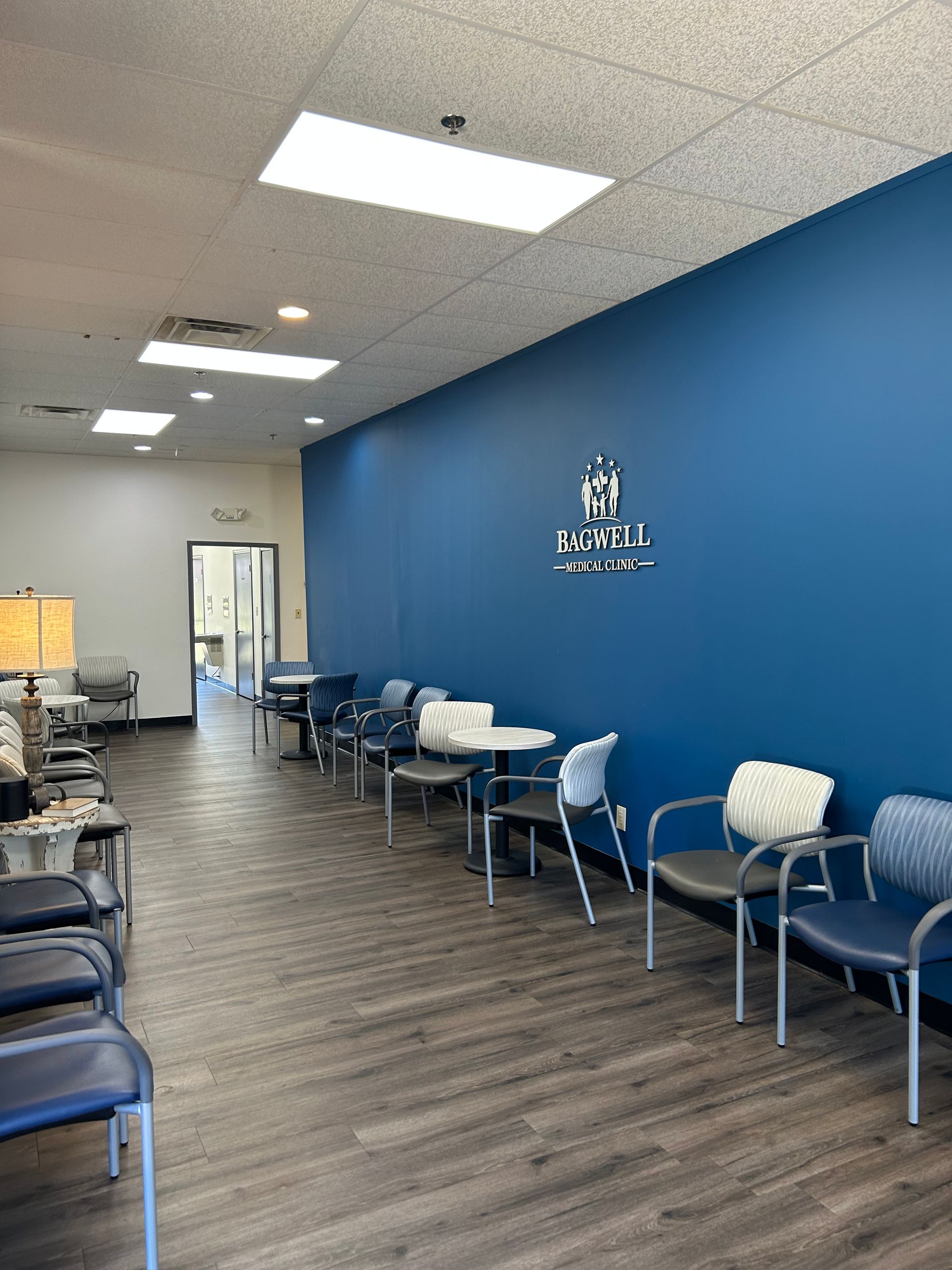 A waiting room with a lot of chairs and tables and a blue wall.