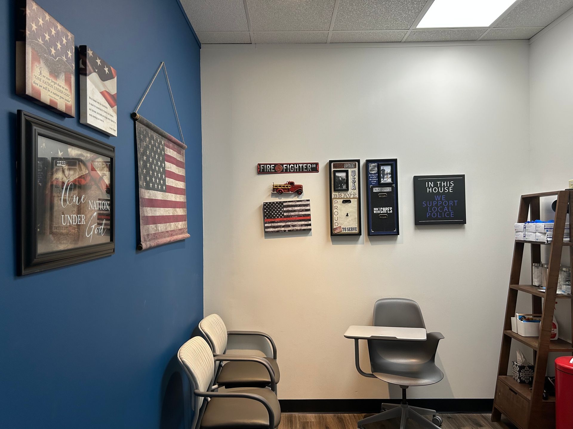 A waiting room with chairs , a desk and a flag on the wall.