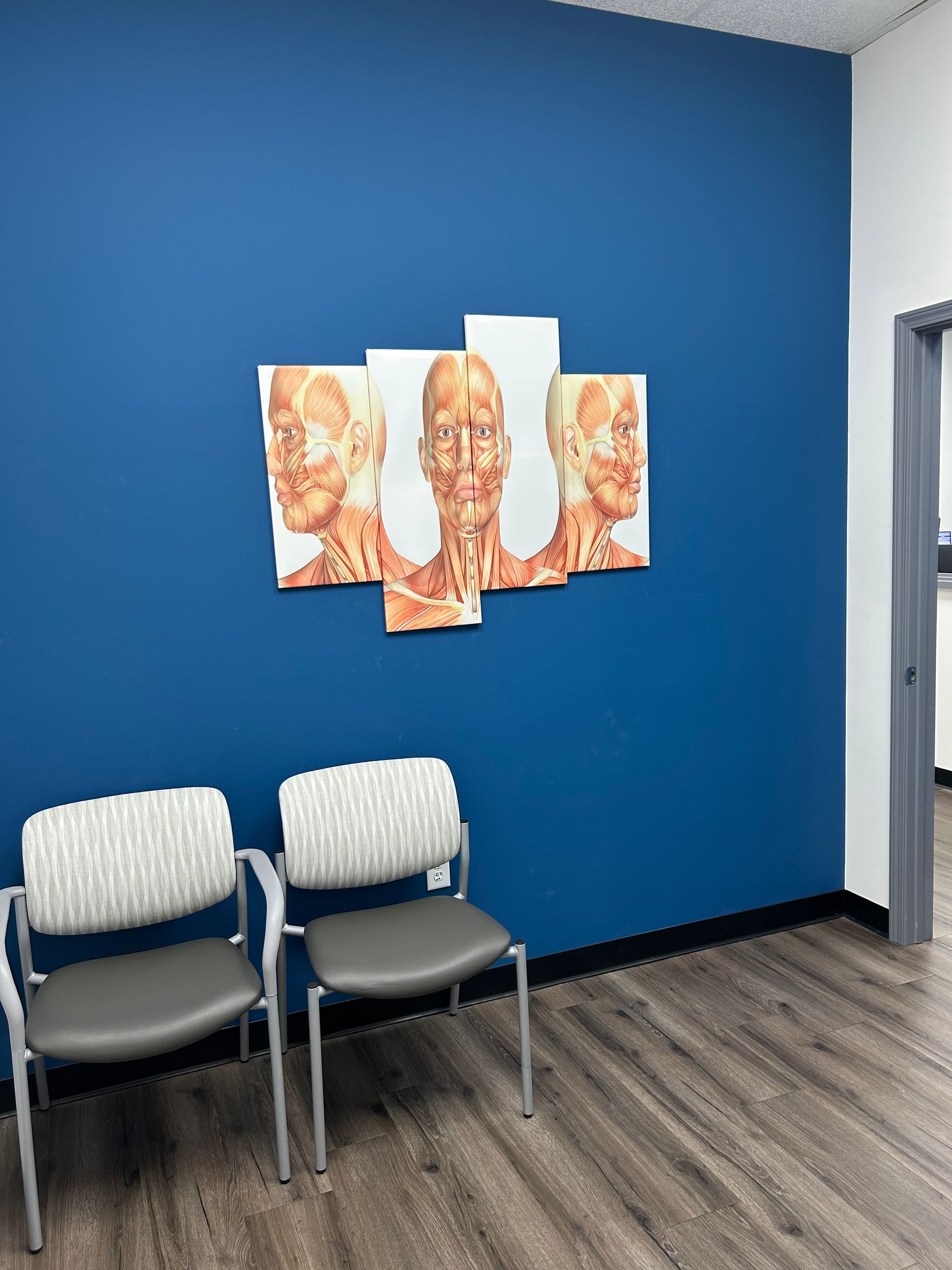 A waiting room with two chairs and a painting on the wall.