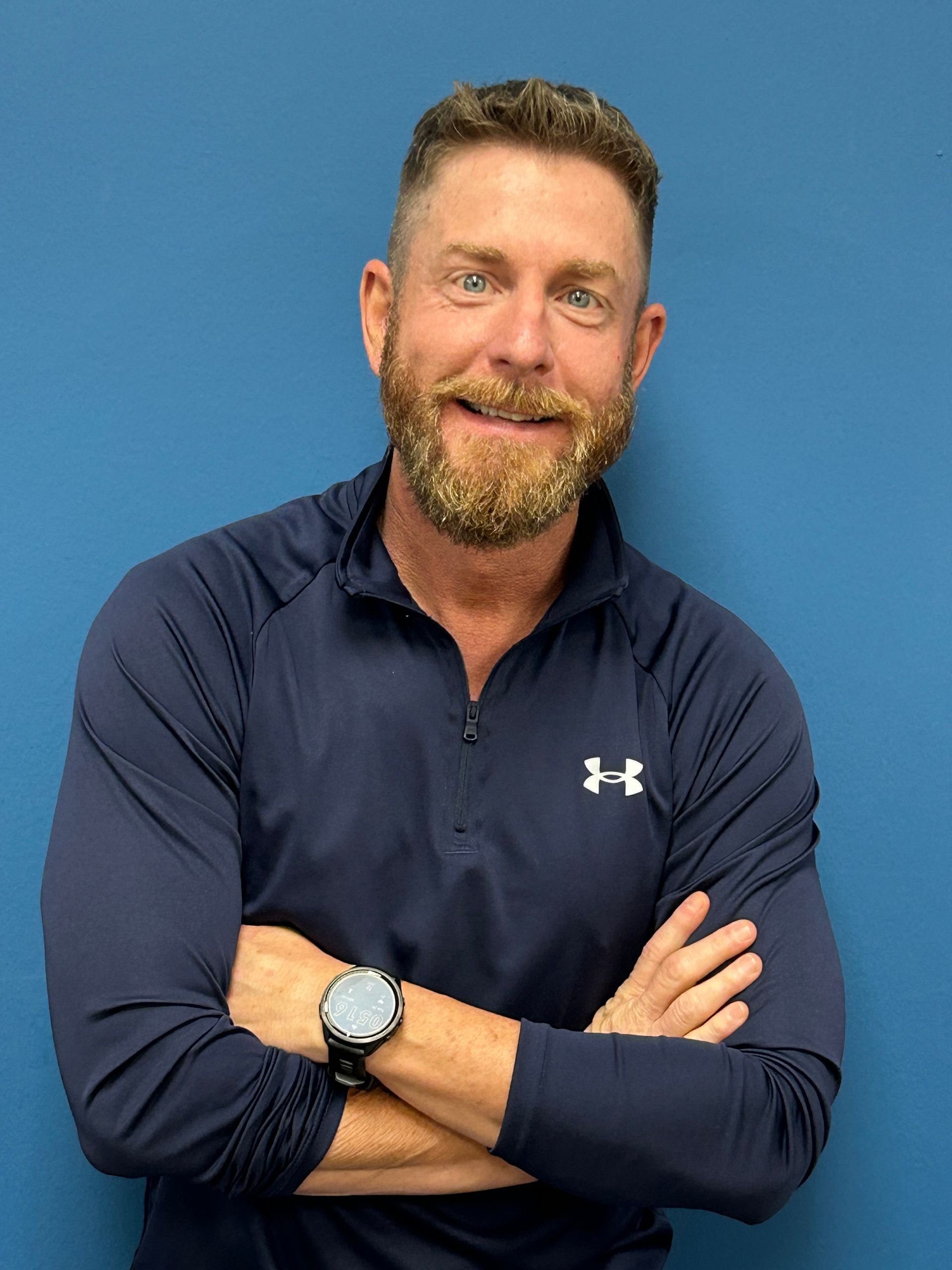 A man with a beard wearing a blue under armour shirt