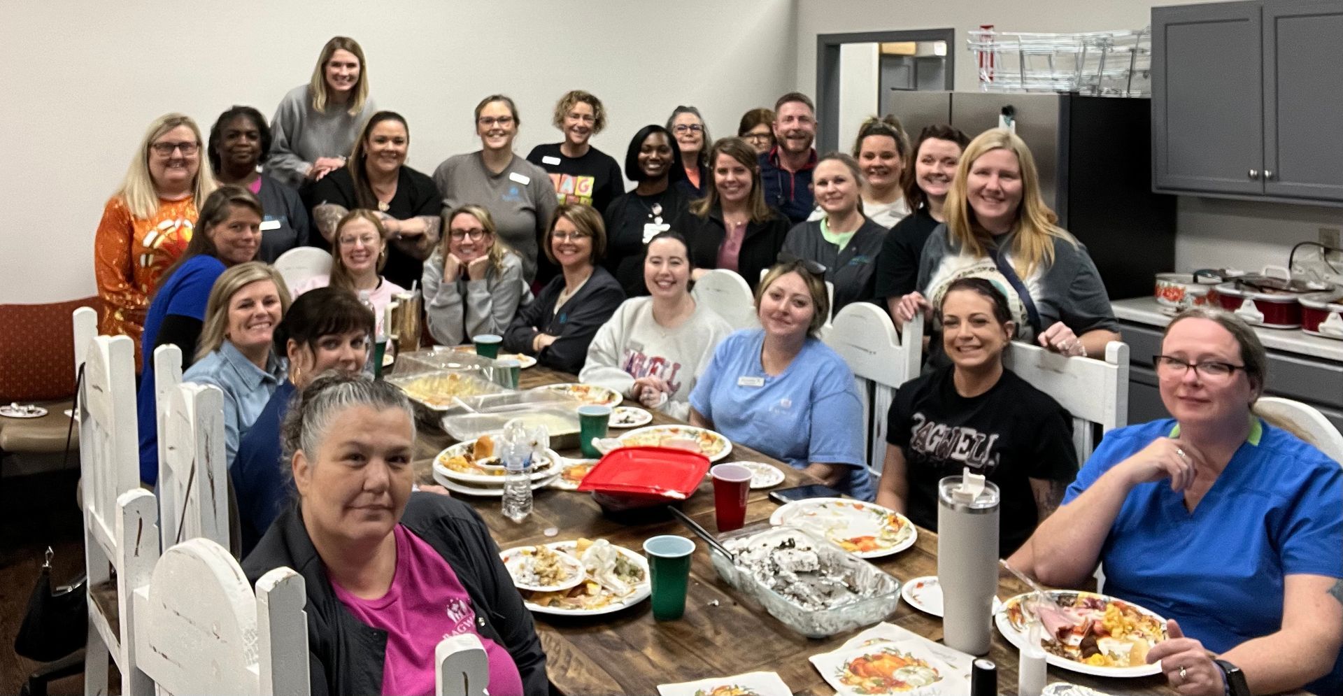 A group of people are sitting around a table with plates of food.