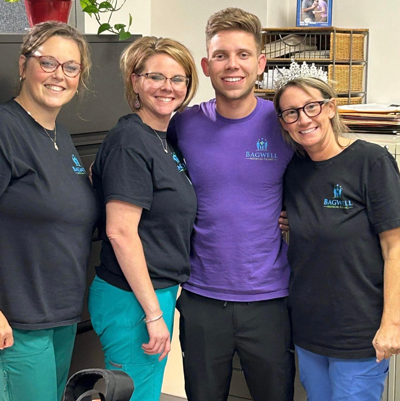 A group of people posing for a picture including a man in a purple shirt