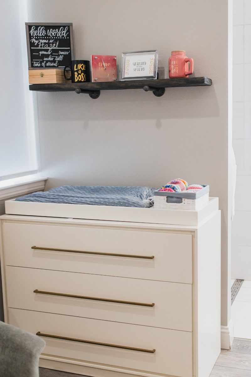 A dresser with a changing table on top of it in a room.