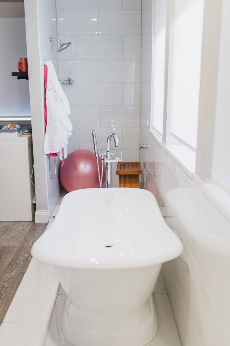 A white bathtub in a bathroom next to a pink exercise ball.