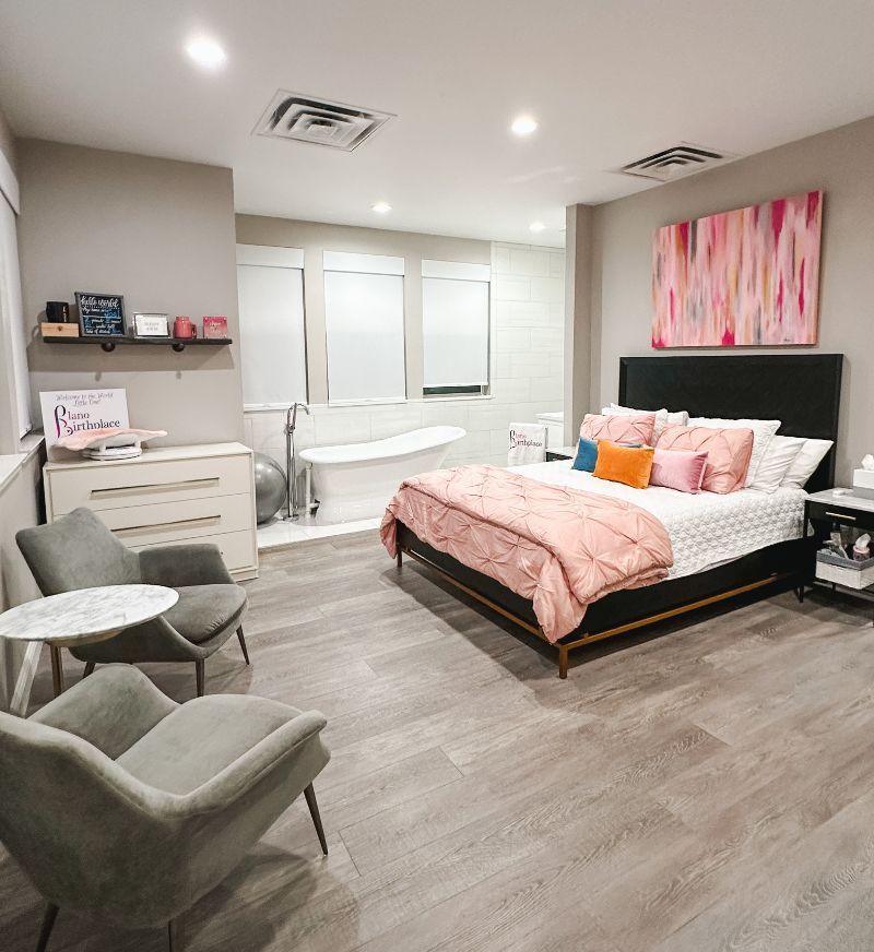 A bedroom with a large bed , chairs , a table and a bathtub.