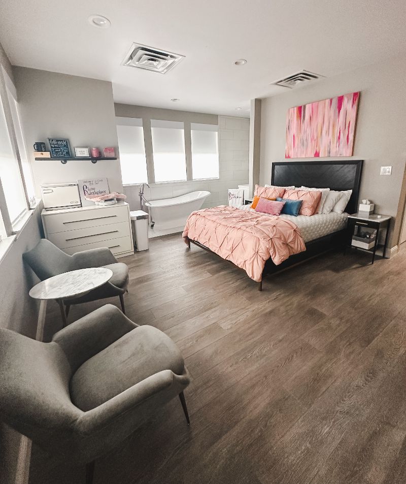 A bedroom with a bed , chairs , a table and a tub.