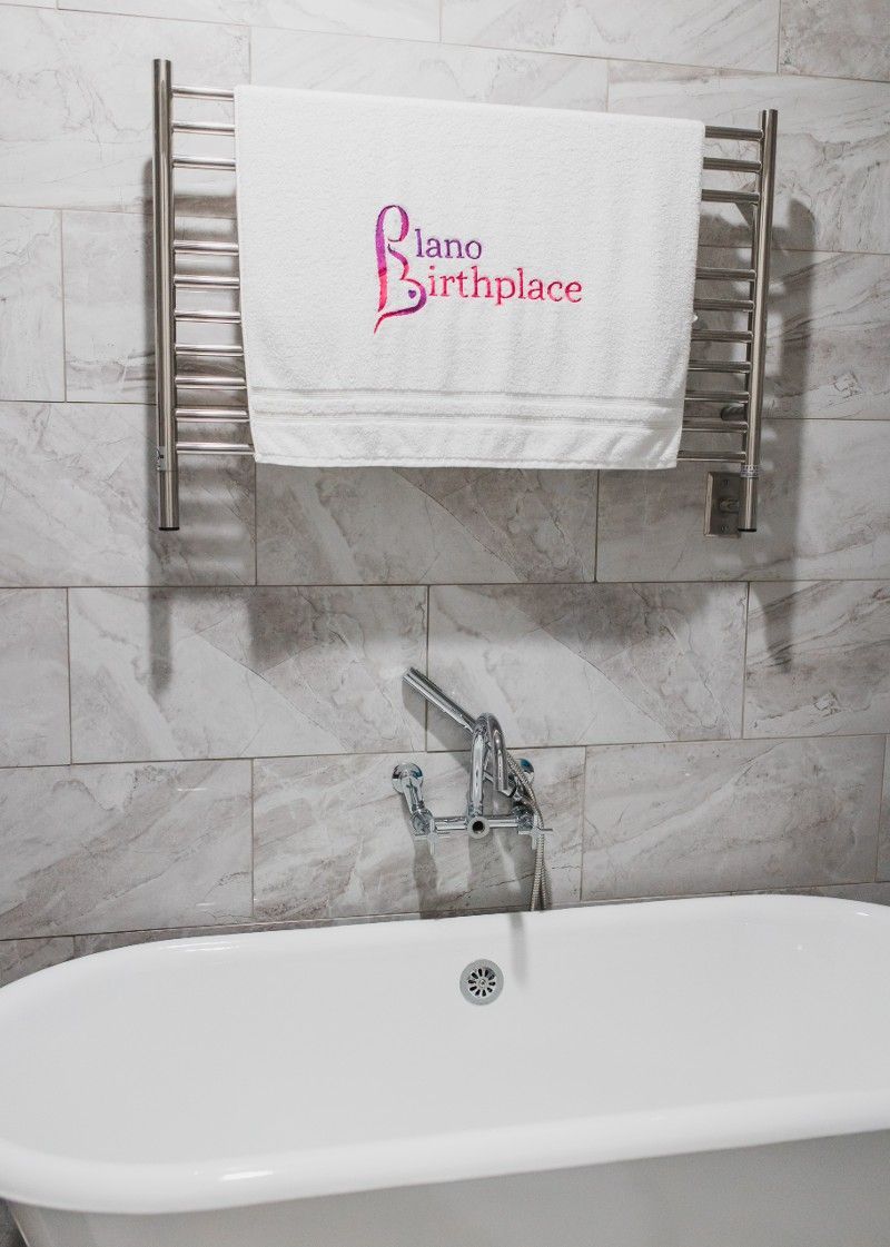 A bathtub in a bathroom with a towel that says birthplace on it