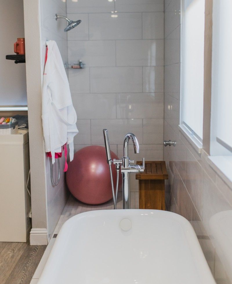 A bathtub in a bathroom next to a pink exercise ball
