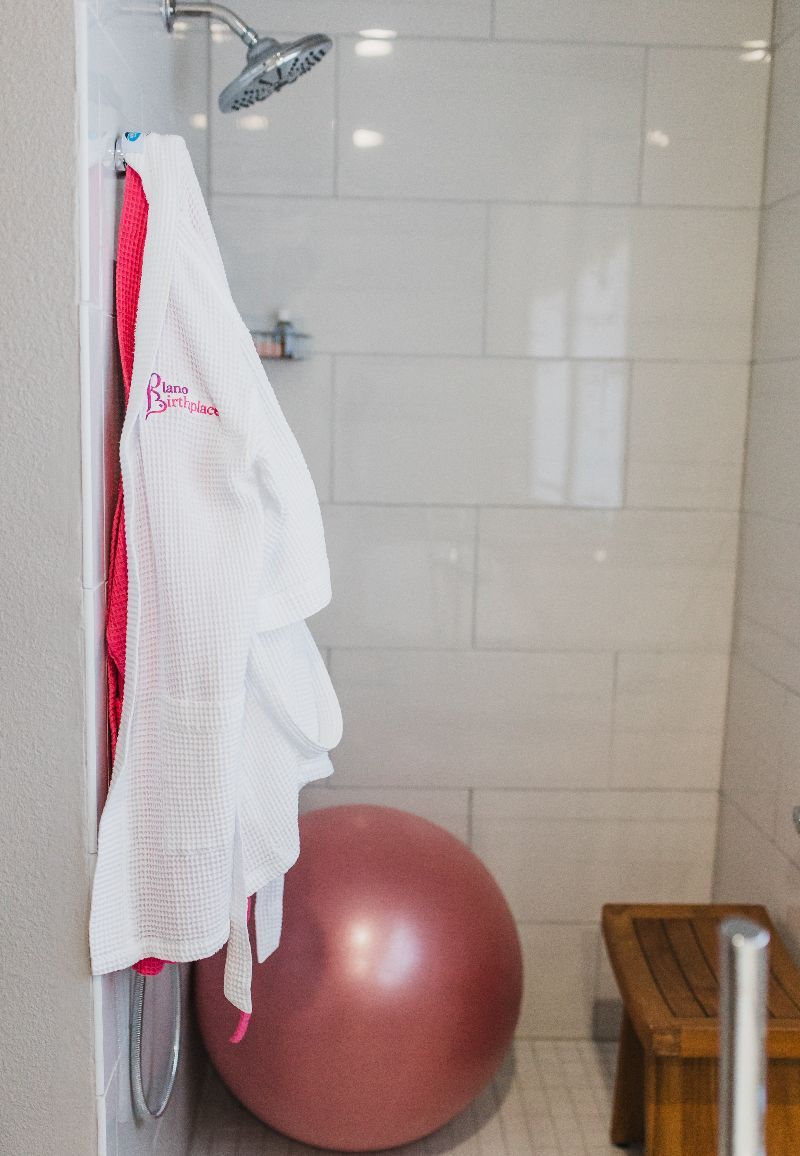 A pink exercise ball is in a bathroom next to a shower.