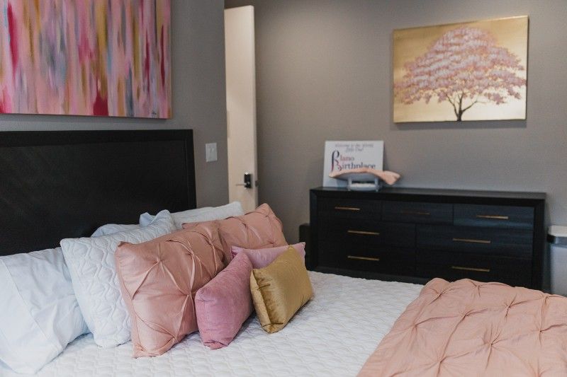 A bedroom with a bed , dresser , and painting on the wall.