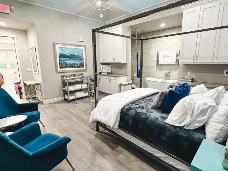 A bedroom with a canopy bed , chairs , and a bathroom.