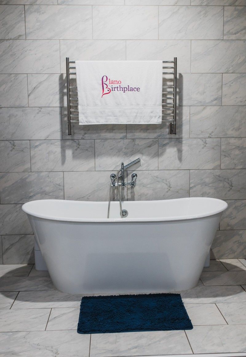 A bathroom with a bathtub and a towel hanging on the wall