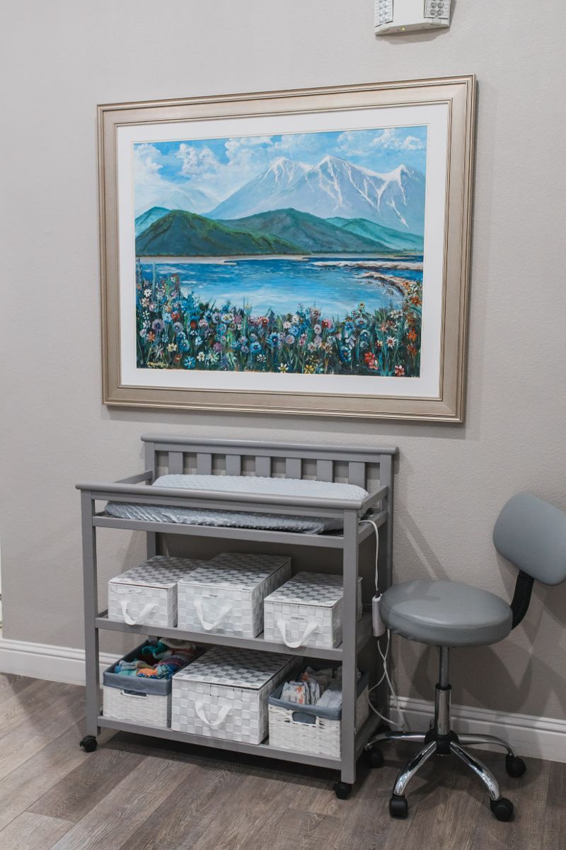 There is a painting on the wall above the changing table.