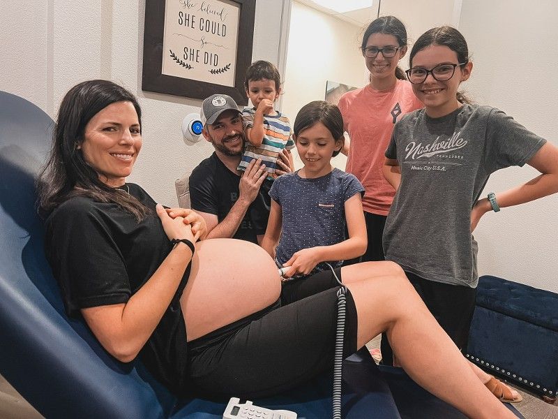 A group of people are standing around a pregnant woman.