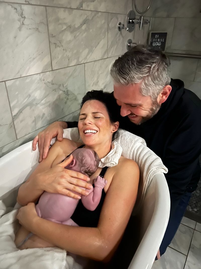 A man and woman are holding a baby in a bathtub