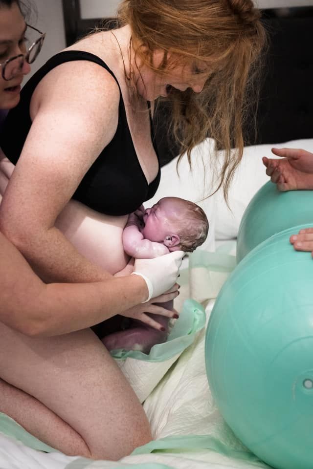 A woman is holding a newborn baby in her arms.