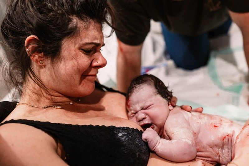 A woman is holding a newborn baby in her arms.