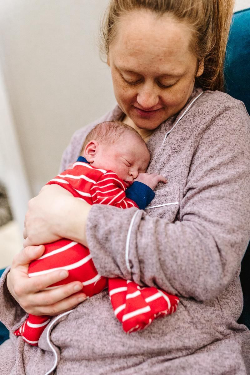 A woman is holding a newborn baby in her arms.